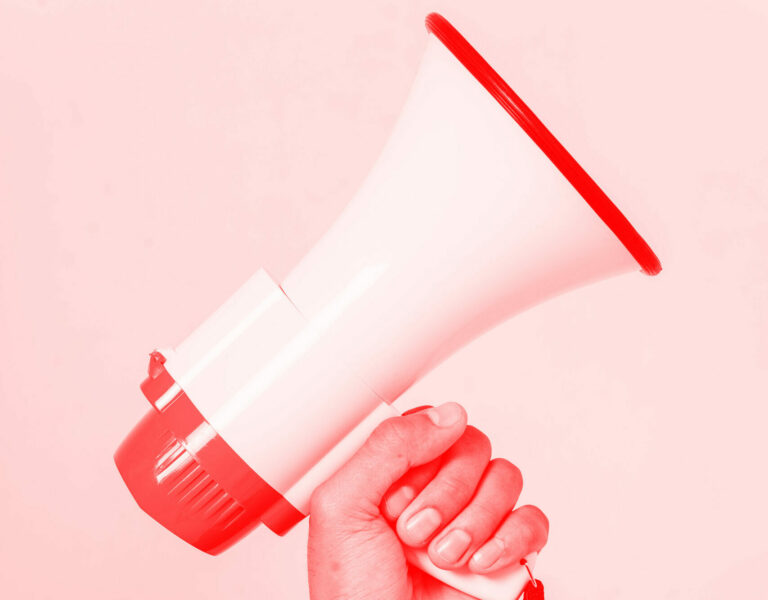 a hand holding a red megaphone on plain background