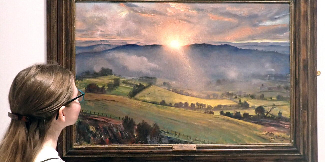 A brunette woman looks at a landscape painting